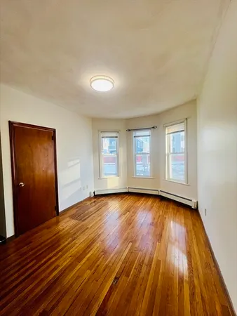 a view of an empty room with wooden floor and window