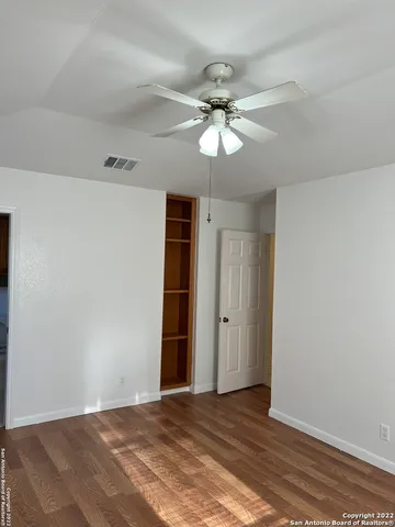 a view of an empty room with a chandelier fan