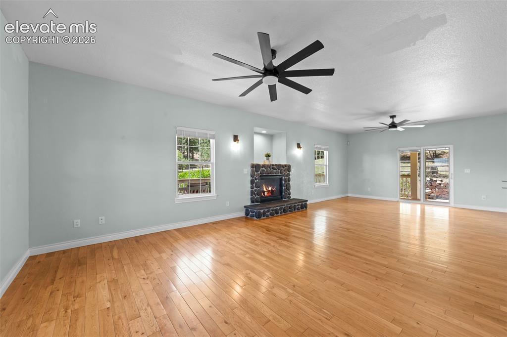 16540 Mesquite Road Peyton, CO 80831 - Photo 6 of 50 a view of empty room with wooden floor and fireplace