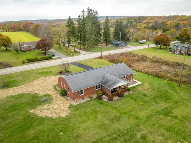an aerial view of a house with pool big yard and large trees