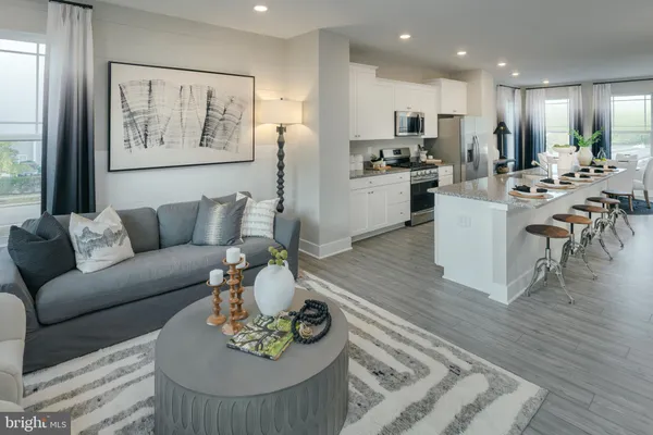 a living room with furniture kitchen and a wooden floor