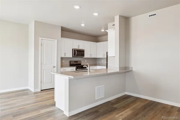 a kitchen with stainless steel appliances a white refrigerator a stove top oven a sink and dishwasher with wooden floor