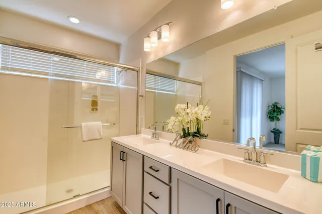 a bathroom with a double vanity sink mirror and shower