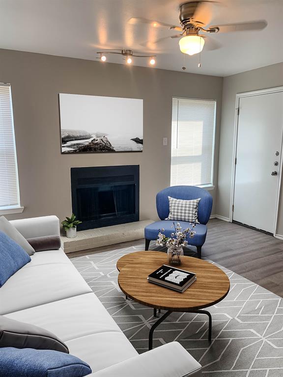 4622 Monarch Street, Unit 106 Dallas, TX 75204 - Photo 1 of 12 Living area featuring wood finished floors, a fireplace with raised hearth, and a ceiling fan