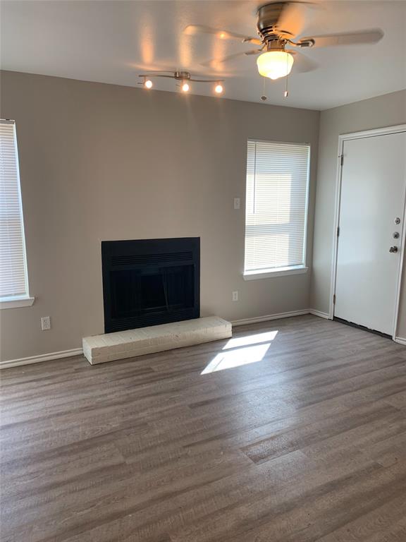 4622 Monarch Street, Unit 106 Dallas, TX 75204 - Photo 5 of 12 Unfurnished living room featuring a fireplace, a ceiling fan, wood finished floors, and track lighting