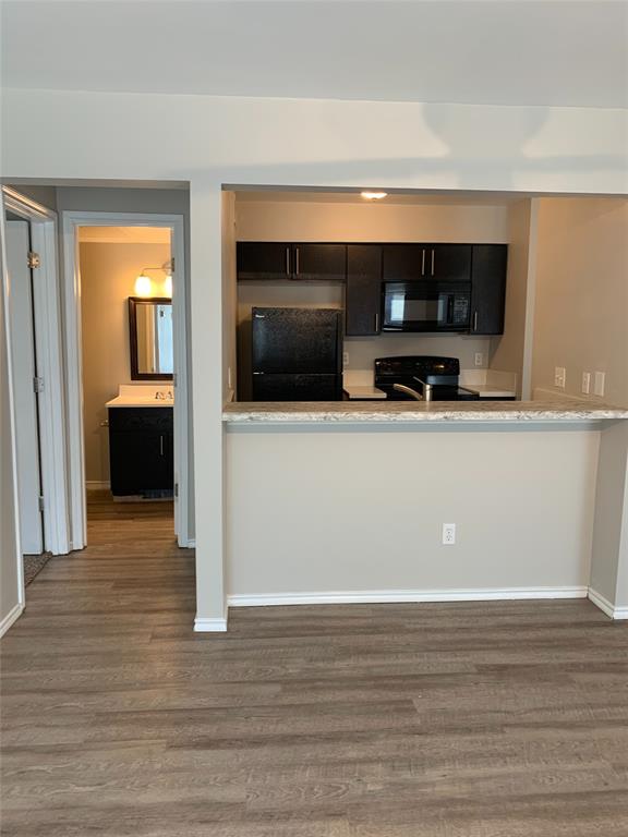 4622 Monarch Street, Unit 106 Dallas, TX 75204 - Photo 9 of 12 Kitchen featuring black appliances, dark wood-style floors, and dark cabinets