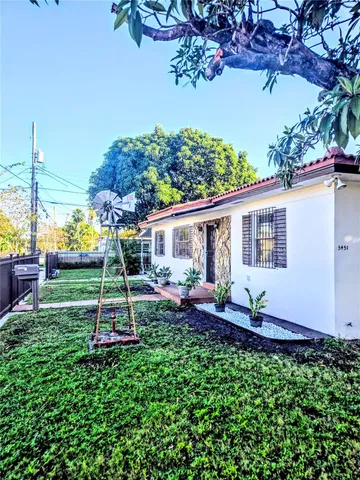 a view of a house with backyard and a tree