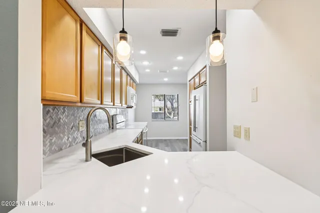 a kitchen with stainless steel appliances kitchen island a sink a refrigerator and cabinets