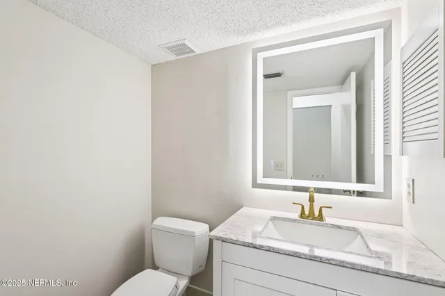 a bathroom with a granite countertop toilet sink and mirror