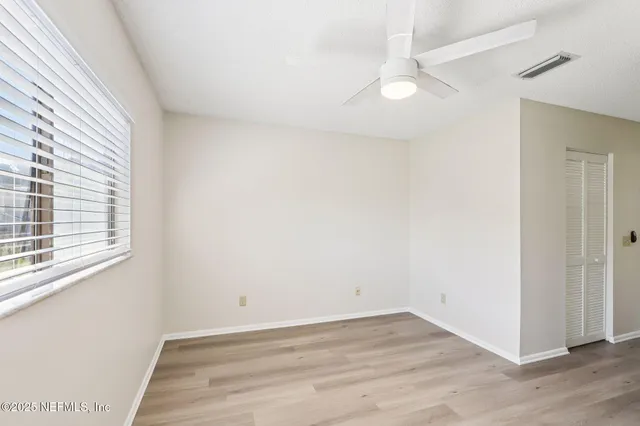 an empty room with wooden floor and windows