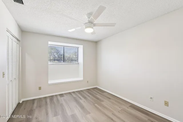 an empty room with a window and a fan