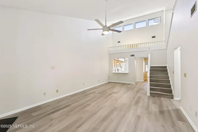 a view of an empty room with wooden floor and stairs