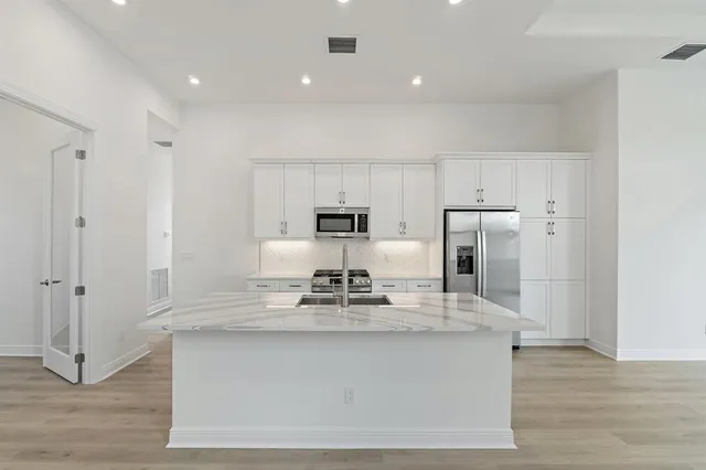 a kitchen with kitchen island stainless steel appliances a sink and refrigerator