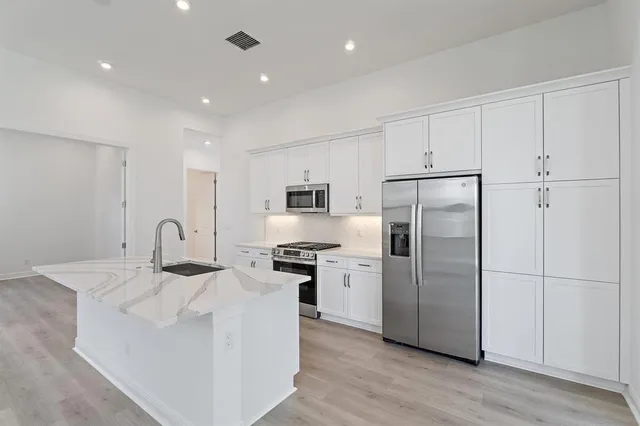 a kitchen with stainless steel appliances granite countertop a refrigerator sink and white cabinets