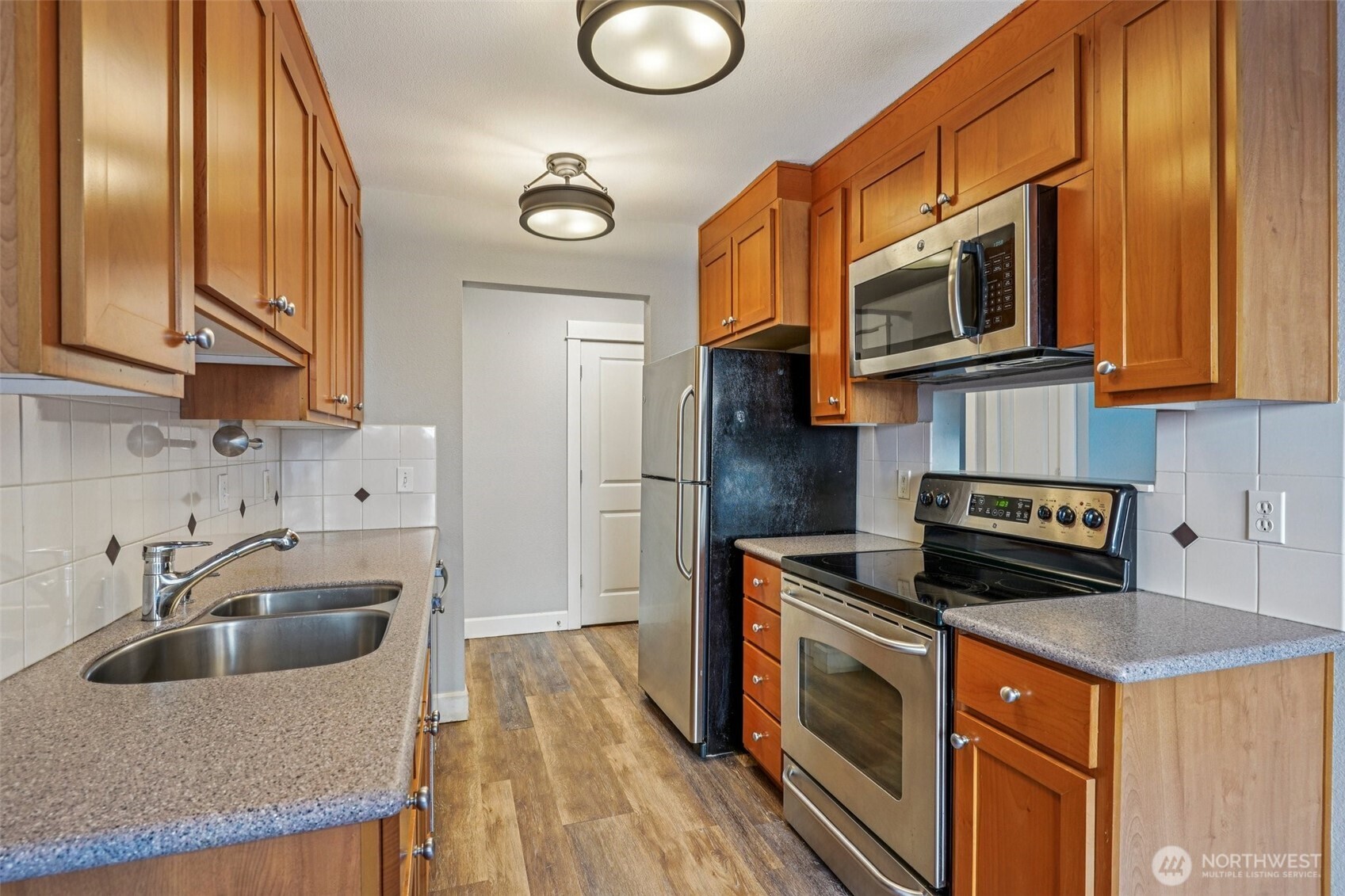 8025 234th Street Southwest, Unit 116 Edmonds, WA 98026 - Photo 7 of 26 a kitchen with stainless steel appliances granite countertop a sink a stove a microwave and cabinets