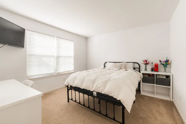 a bedroom with a bed and a flat tv screen on dresser