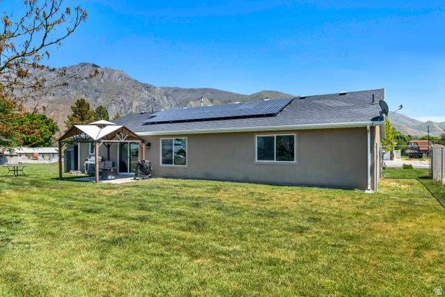 65 North 450 West Springville, UT 84663 - Photo 31 of 32 Expansive rear yard featuring a covered patio, multiple windows, and solar panels on the roof