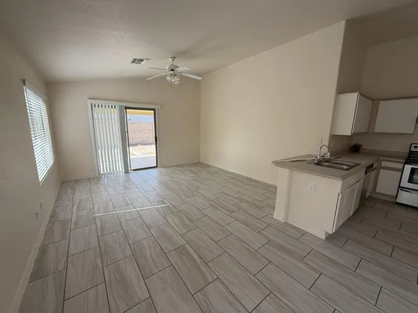 a view of kitchen and empty room with wooden floor