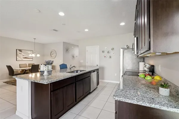 a kitchen with stainless steel appliances granite countertop a stove top oven a sink a dining table and chairs