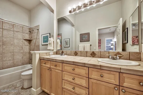 a bathroom with a granite countertop sink mirror vanity bathtub and toilet