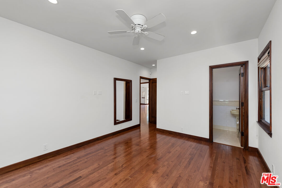 1039 Hi Point Street Los Angeles, CA 90035 - Photo 16 of 27 a view of an empty room with wooden floor and a ceiling fan