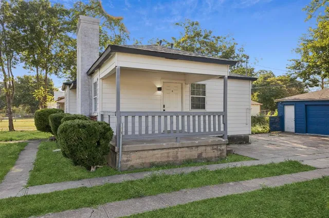a view of a house with a yard and large tree