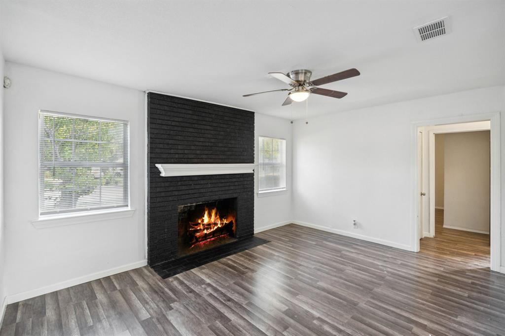 3228 Emmett Street Dallas, TX 75211 - Photo 4 of 25 a view of an empty room with wooden floor fireplace and a window
