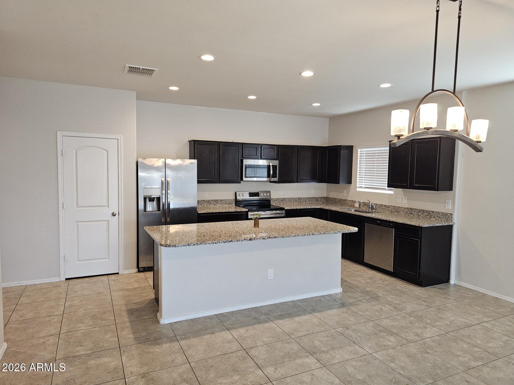 25573 West Coles Road Buckeye, AZ 85326 - Photo 3 of 12 a large kitchen with a large counter top stainless steel appliances and cabinets