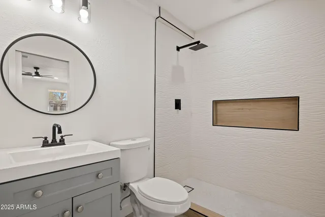 a bathroom with a sink a mirror a toilet and a shower