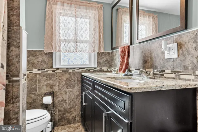 a bathroom with a granite countertop sink a toilet and a mirror