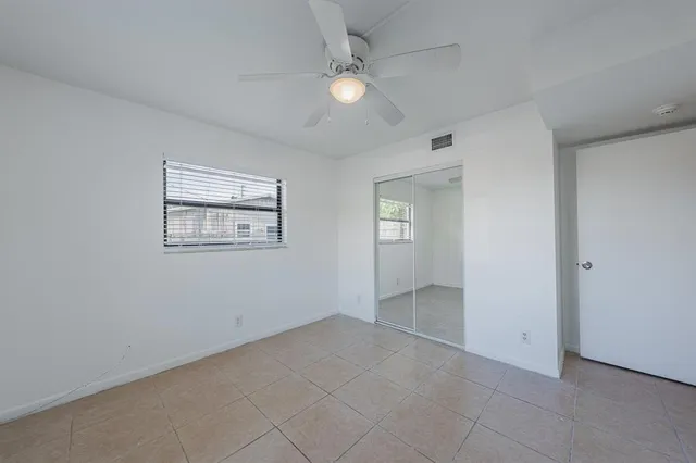 an empty room with windows and fan