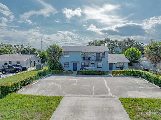 a view of a big yard in front of a brick house with a large tree