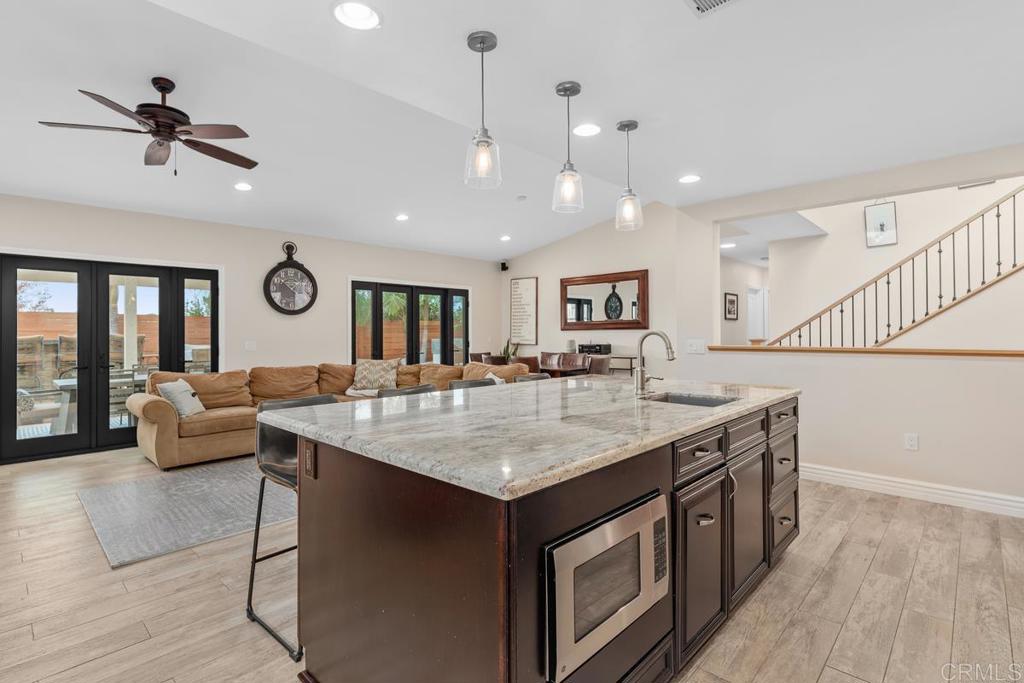 262 Chapalita Drive Encinitas, CA 92024 - Photo 7 of 30 a hall with kitchen island stainless steel appliances wooden floor dining table and chairs