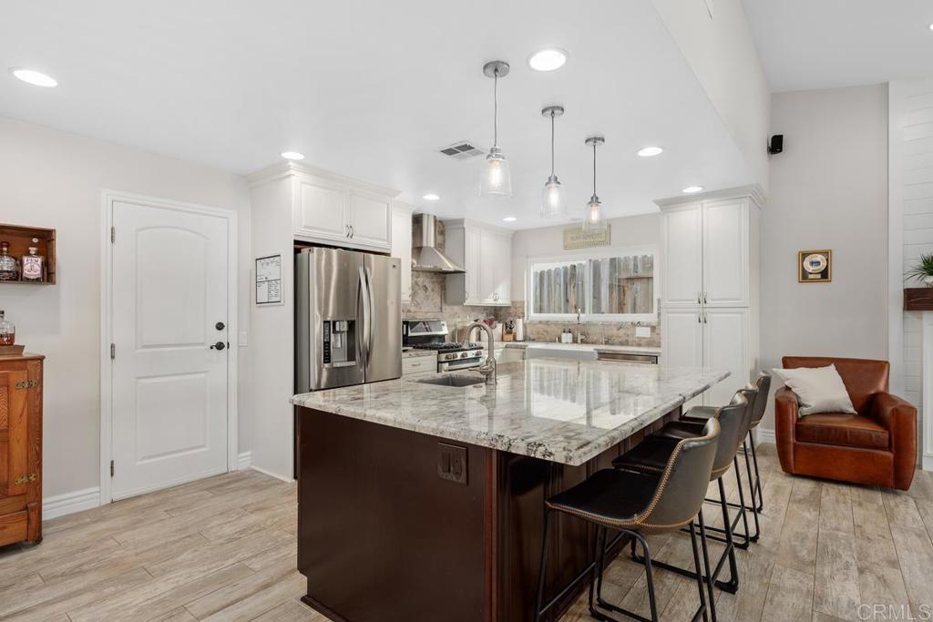 262 Chapalita Drive Encinitas, CA 92024 - Photo 9 of 30 a kitchen with stainless steel appliances kitchen island granite countertop a table chairs in it and wooden floors