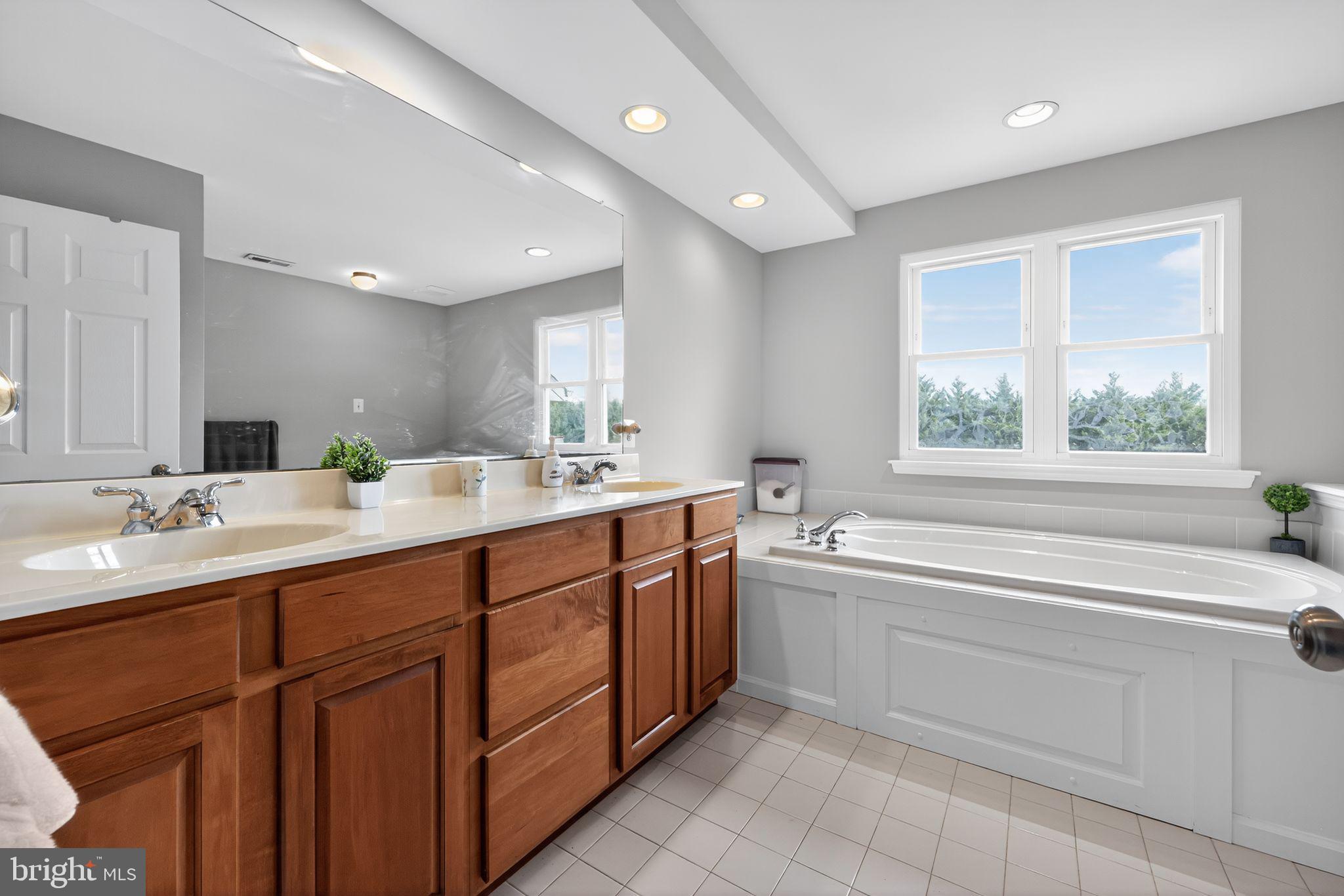 562 Partridge Court Mickleton, NJ 08056 - Photo 24 of 33 a bathroom with a double vanity sink a large mirror and a bathtub