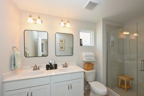 a bathroom with a toilet sink vanity shower and mirror