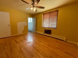 a view of an empty room with window and wooden floor
