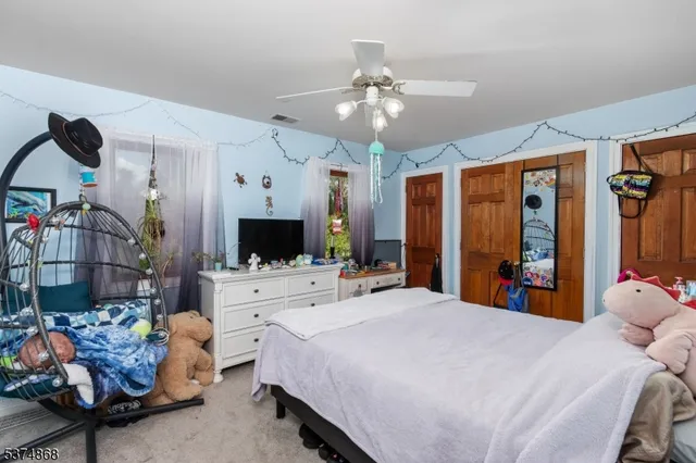 a large bedroom with a bed and a flat tv screen on the dresser