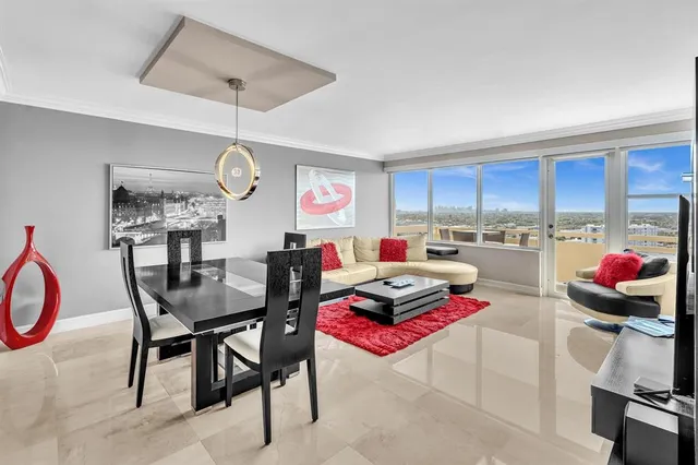 a kitchen with stainless steel appliances kitchen island granite countertop a dining table chairs and a refrigerator