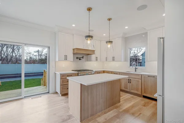 a large kitchen with stainless steel appliances granite countertop a stove a sink a refrigerator and a wooden cabinets