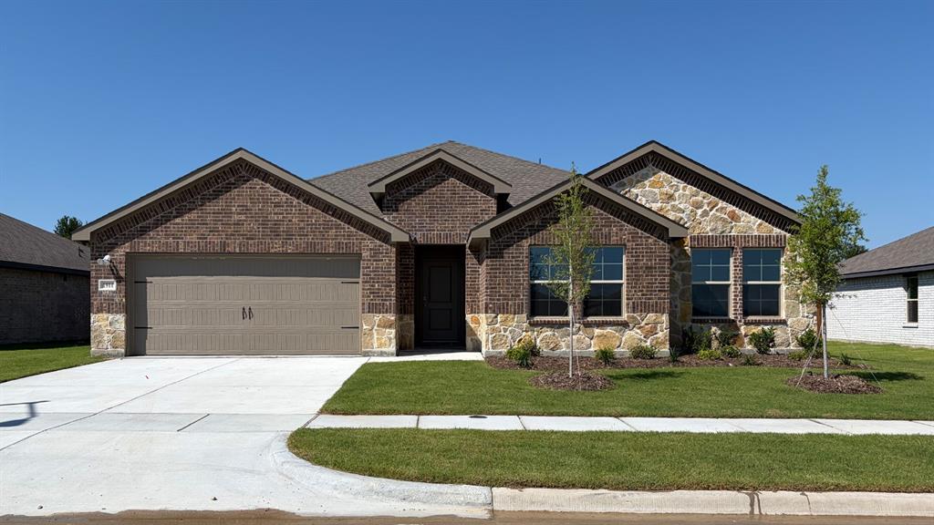 1911 Reveille Way Terrell, TX 75160 - Photo 1 of 39 Brick and stone facade residence featuring a two-car garage, concrete driveway, and a landscaped front yard with young trees
