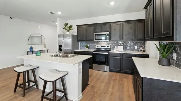 a view of living room kitchen with stainless steel appliances granite countertop a sink and a refrigerator
