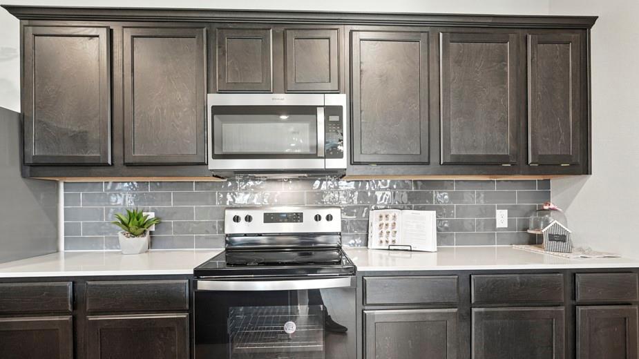 1911 Reveille Way Terrell, TX 75160 - Photo 14 of 39 Kitchen featuring stainless steel appliances, decorative backsplash, dark wood finish cabinets, and light stone counters