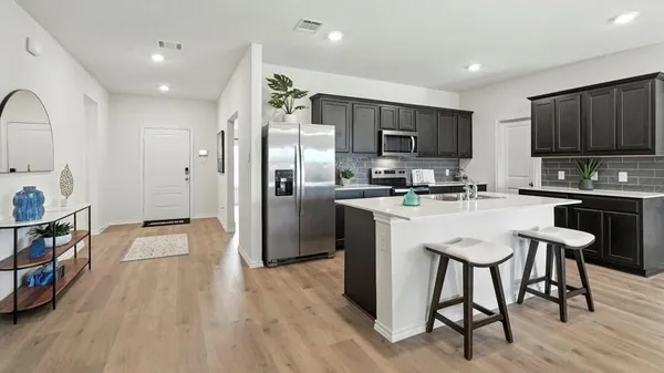 a kitchen with stainless steel appliances a sink a microwave a refrigerator and a stove top oven