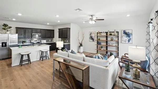 a living room with furniture kitchen view and a wooden floor