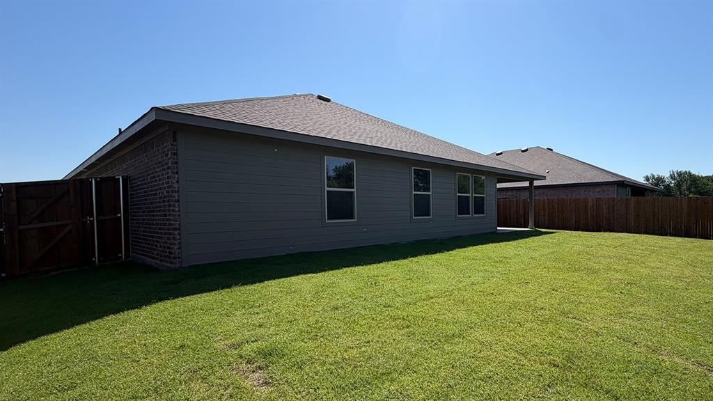 1911 Reveille Way Terrell, TX 75160 - Photo 35 of 39 Expansive green lawn surrounds the property, featuring a privacy fence and a covered patio area