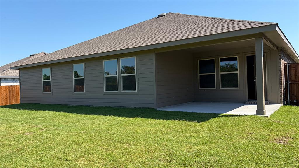 1911 Reveille Way Terrell, TX 75160 - Photo 37 of 39 Rear exterior featuring a covered concrete patio, grey horizontal siding, numerous windows, a brown shingle roof, and a wood fence