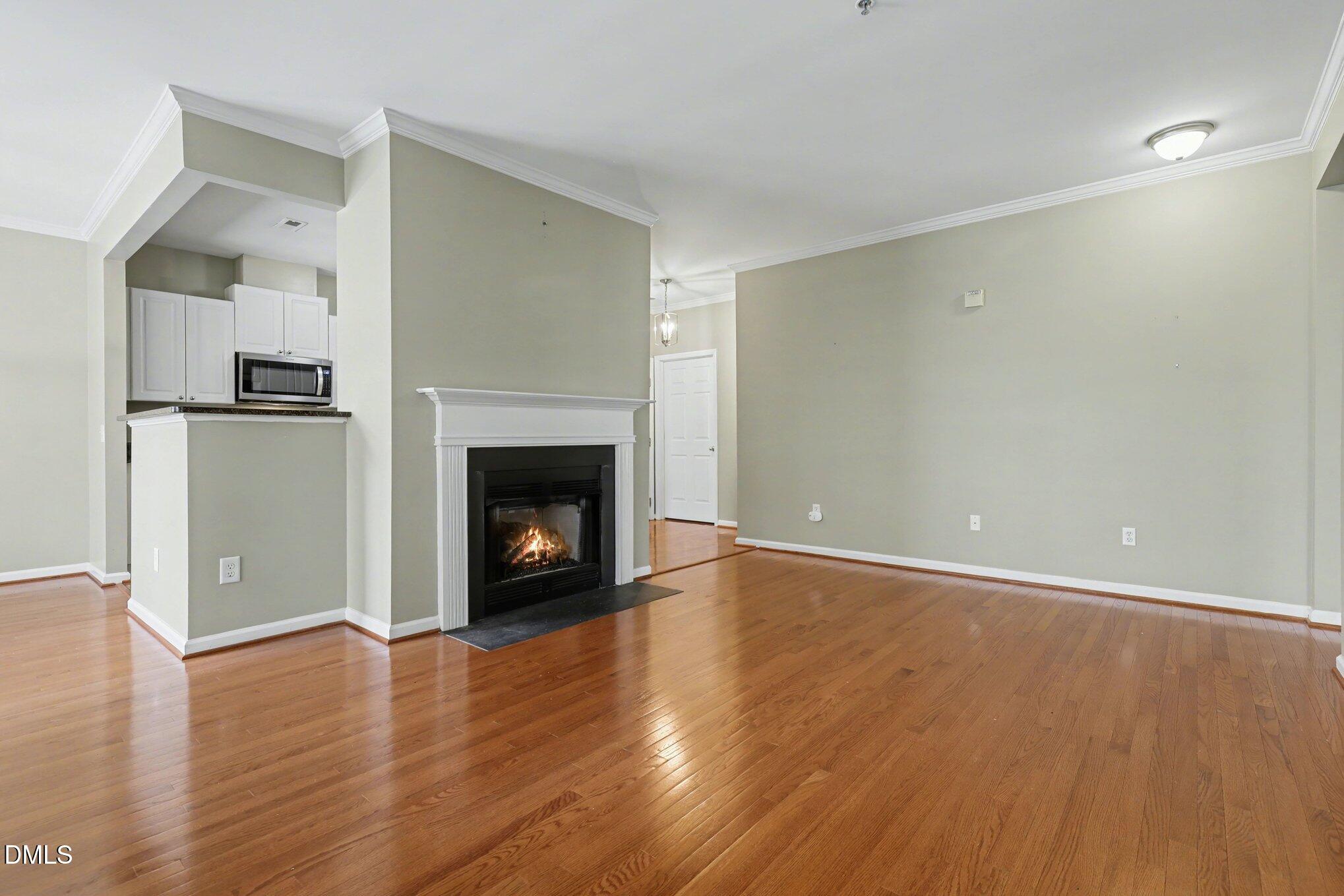 3121 Hemlock Forest Circle, Unit 203 Raleigh, NC 27612 - Photo 15 of 33 a view of an empty room with wooden floor fireplace and a window