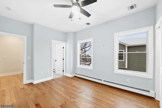 a view of an empty room with window and wooden floor