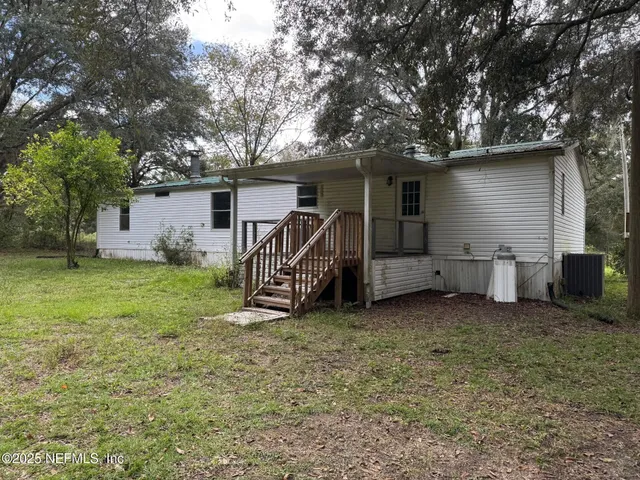 a view of a house with a yard and a large tree